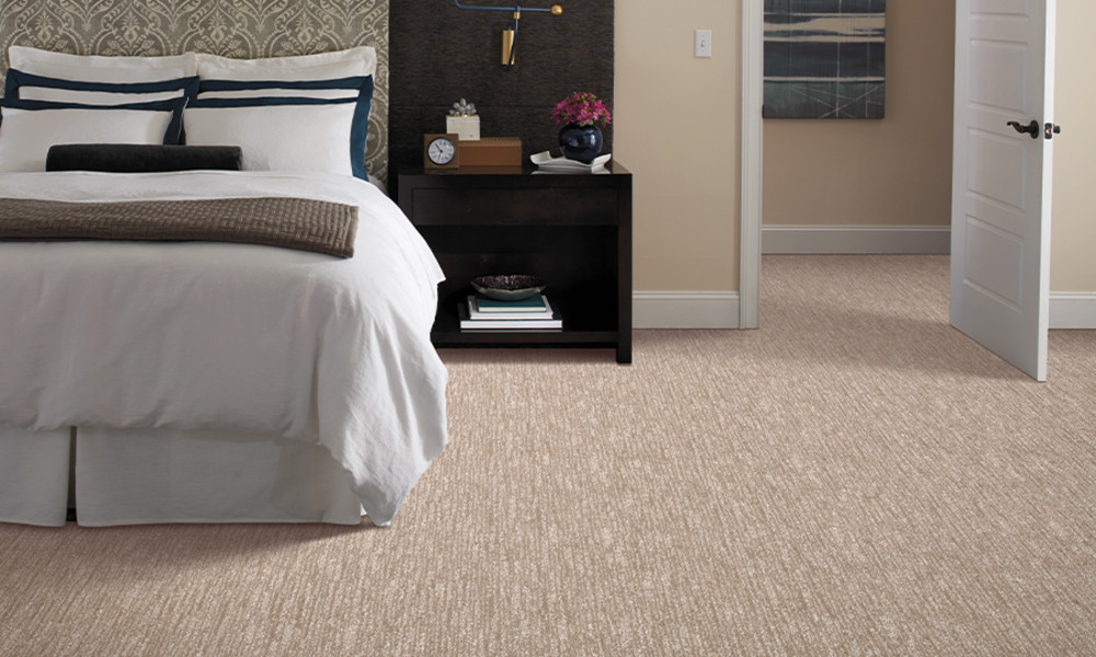 Tan carpet in a bedroom with white bedding