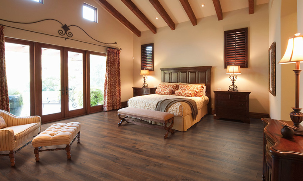 Dark wood laminate flooring in a bedroom with vaulted ceiling